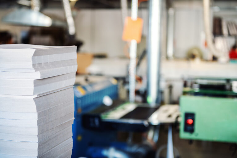 Picture of printing shop interior. Selective focus on pile of sheets.